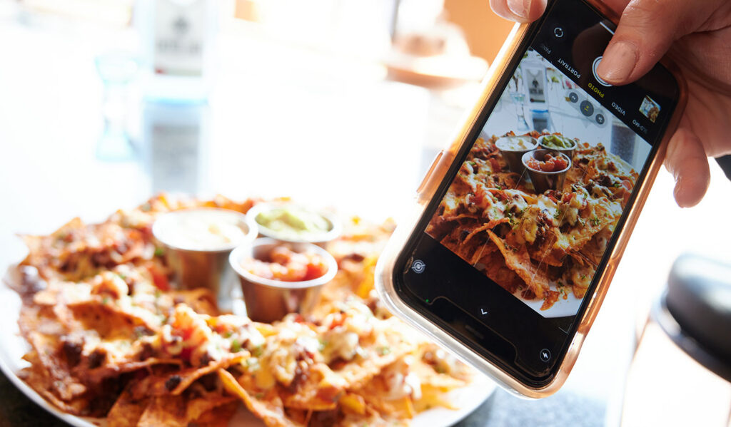 Influencer taking picture of Beef Nachos on a smartphone in the Zagora grill room restaurant