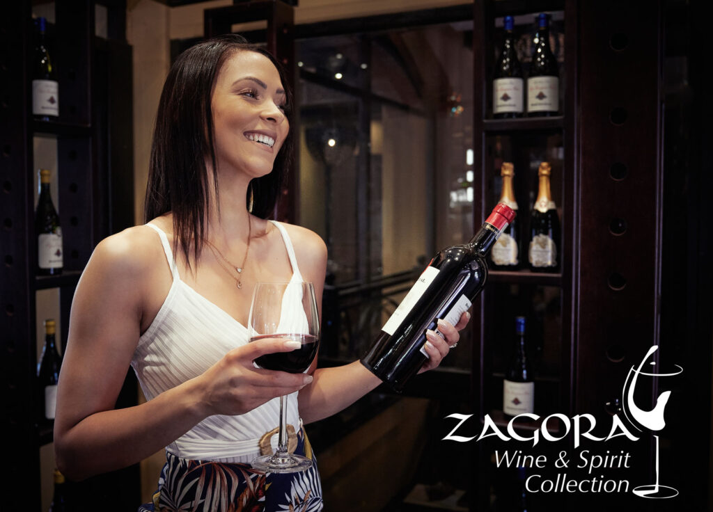 Woman standing with a glass and bottle of wine in the Zagora Wine and Spirit Collection